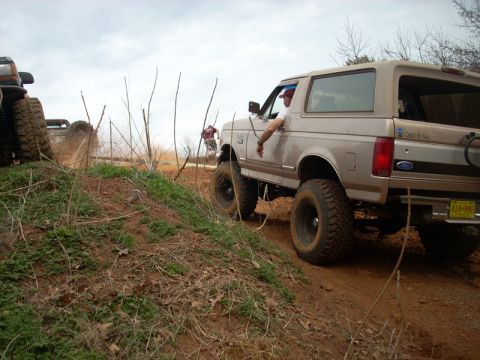 1996 Ford Bronco - A tan Ford Bronco navigates an off-road trail with another vehicle visible in the background.