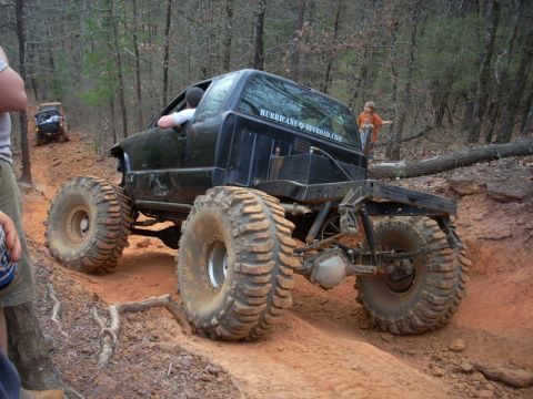 1996 Ford Bronco - A heavily modified truck navigates a wooded trail with another vehicle visible in the background.