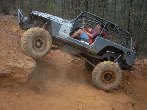 1996 Ford Bronco - A modified Jeep Wrangler navigates a challenging off-road trail, demonstrating its extreme suspension and tire capabilities.