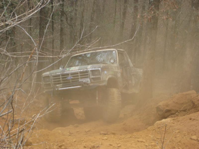 Lifted 1980s Ford truck kicking up dust on a dirt trail
