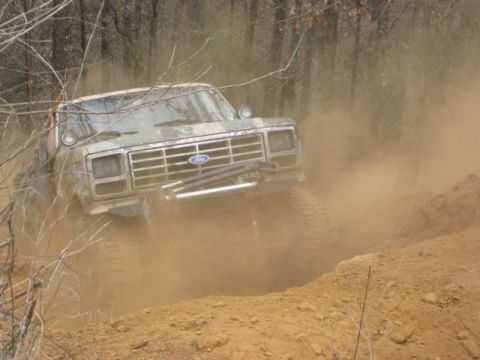 1996 Ford Bronco - A lifted Ford truck navigates a dusty off-road course.