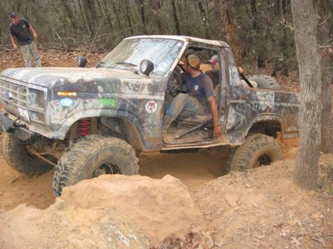1996 Ford Bronco - This heavily modified truck appears to be from the 1980s, not a 1996 Ford Bronco, as it navigates a challenging off-road course.