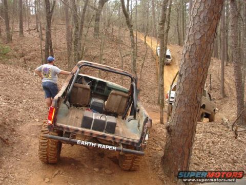 1996 Ford Bronco - Multiple off-road vehicles navigate a muddy trail through a dense forest.