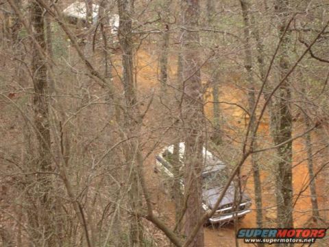 1996 Ford Bronco - A vehicle navigates a wooded trail with an orange dirt surface.