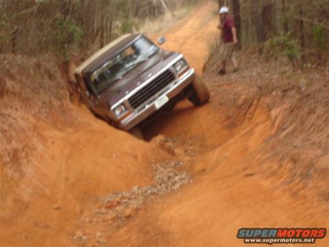 1996 Ford Bronco - Ford Bronco struggling on a challenging off-road trail with a person watching.