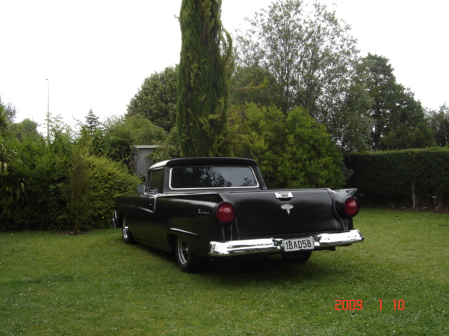 1958 Ford Ranchero parked on grass, rear view. License plate reads 1BAD58
