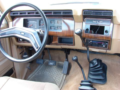 1984 Ford F-250 - The interior of a 1984 Ford F-250 XLT features wood grain trim and a dual-stick manual transmission setup.