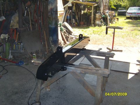 1989 Ford Bronco - A black rear bumper is being worked on, supported by wooden sawhorses.