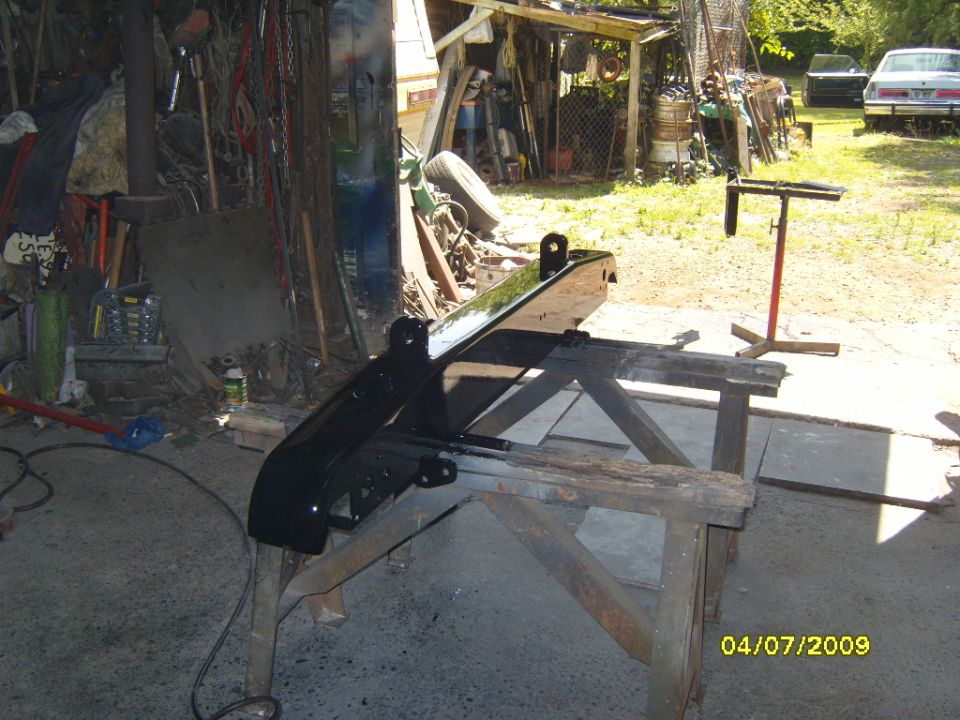 Black rear bumper mounted on wooden sawhorses in a garage setting
