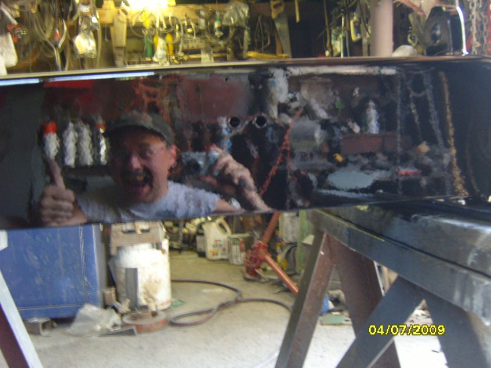 Man in garage with spray can and thumbs up, reflected in a shiny surface