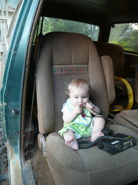 1990 Ford Bronco - A baby sits in the passenger seat of a vehicle, playing with a cord while a CB radio rests nearby.