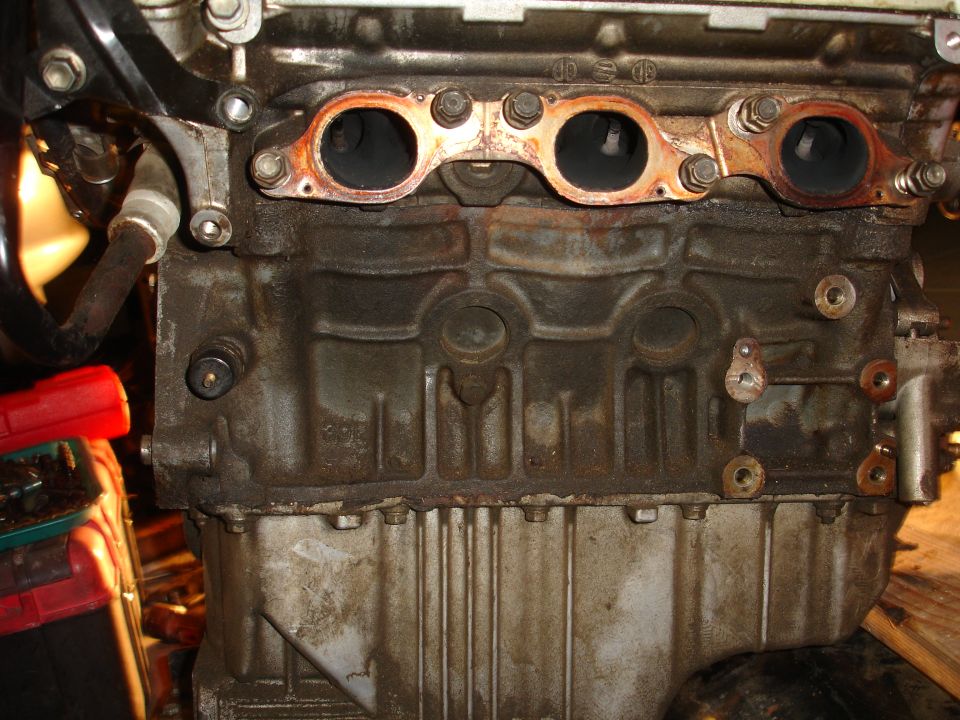 Close-up of an engine block with exhaust ports and manifold attached