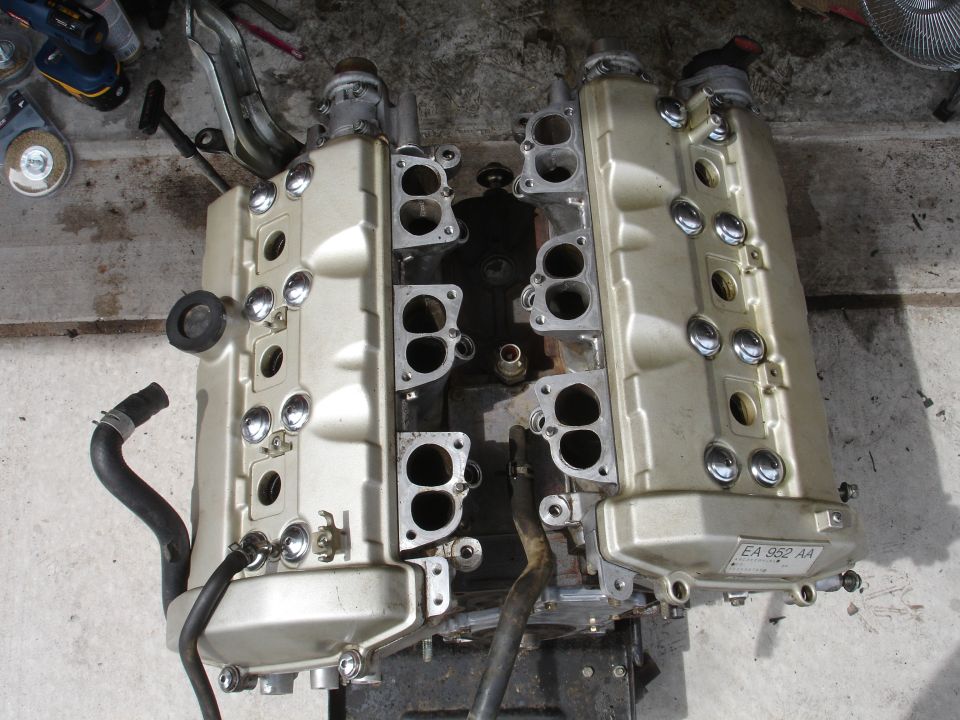 Engine valve covers with intake manifold ports, one has a label reading EA 952 AA