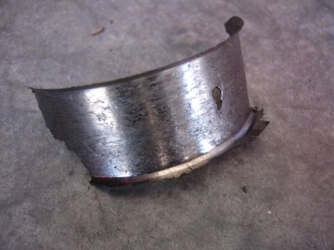 1992 Ford Taurus - A damaged engine bearing shows significant wear and a hole, indicating mechanical failure.
