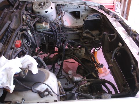 1992 Ford Taurus - Engine bay stripped down for a rebuild, showing exposed wiring and engine components.