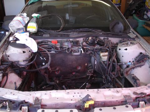 1992 Ford Taurus - The engine bay of a car is shown with the engine removed, revealing the internal components and wiring.