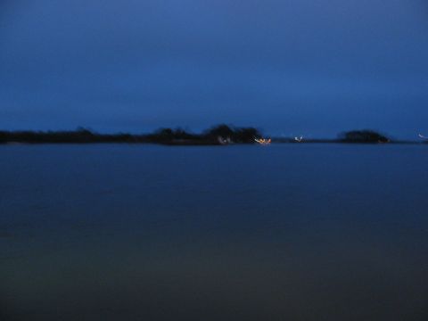 1985 Ford LTD Crown Victoria - A distant shoreline with lights is visible across dark water under a twilight sky.