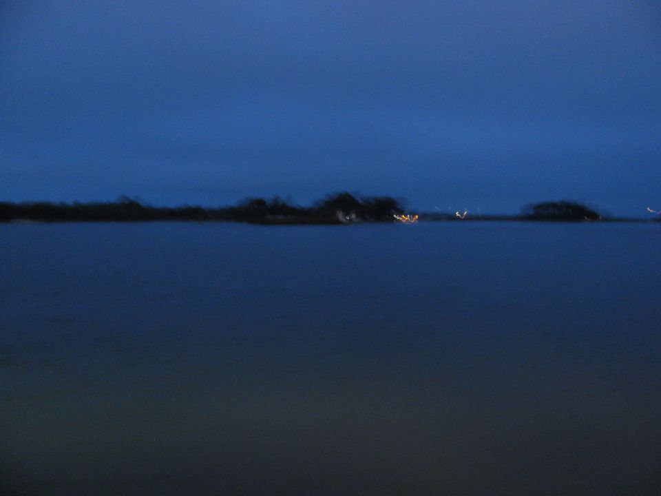 Water and distant lights under a dark blue sky