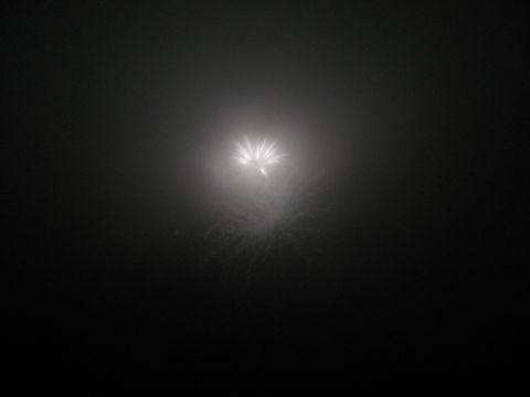 1985 Ford LTD Crown Victoria - A bright firework bursts against a dark, hazy night sky.