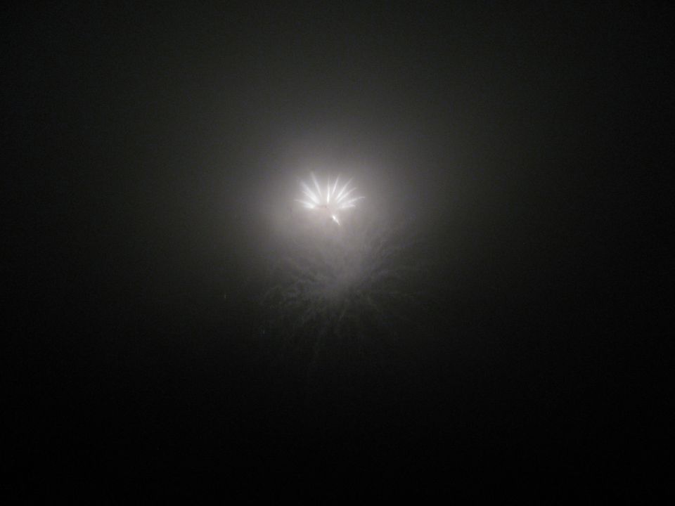 Fireworks exploding in a dark, foggy sky