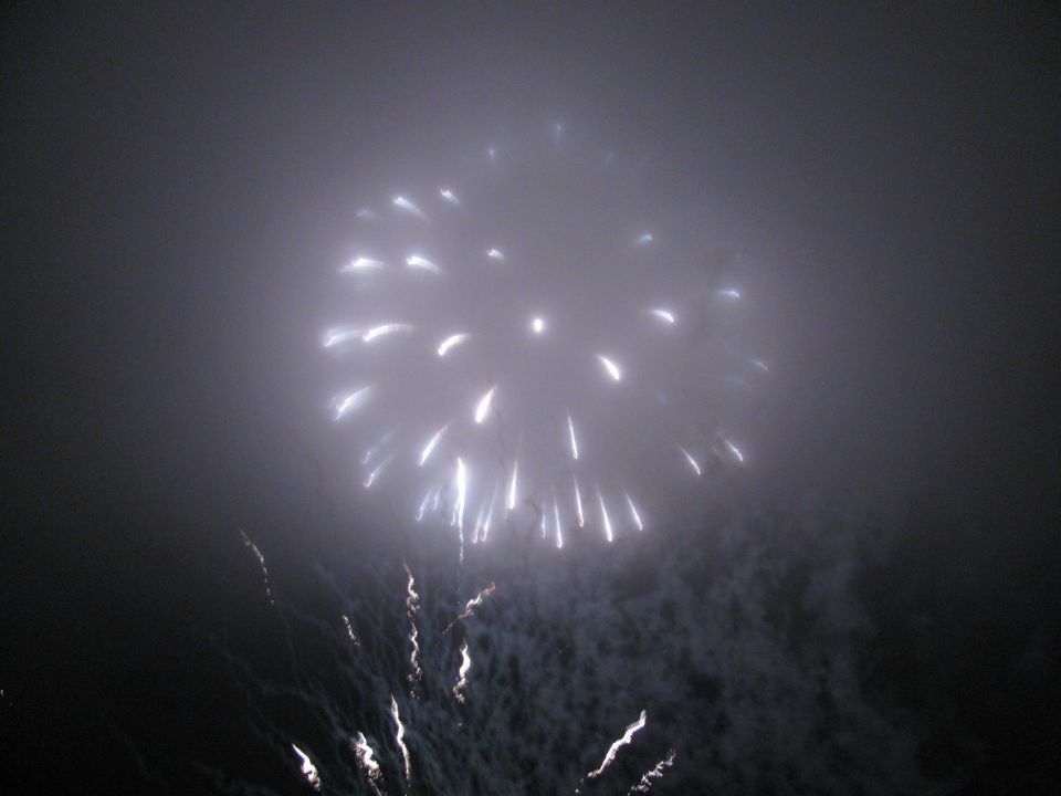 Fireworks explode in a foggy night sky