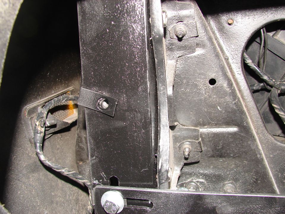 Close-up of a black metal mounting bracket and wiring in a vehicle's inner fender well