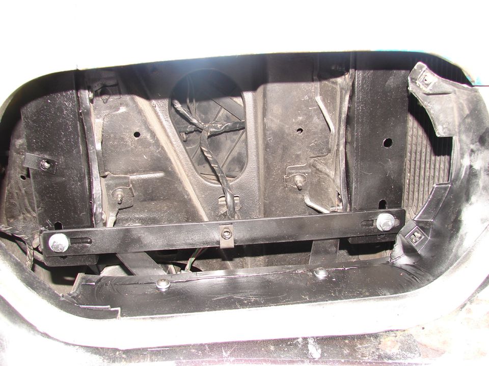 Black radiator core support with bolt-on crossbar seen through an empty grille opening