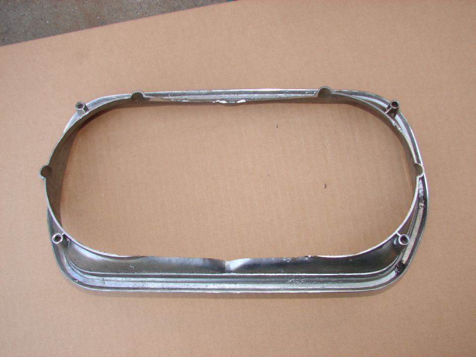Chrome oval bezel trim ring removed from a car, laid on cardboard