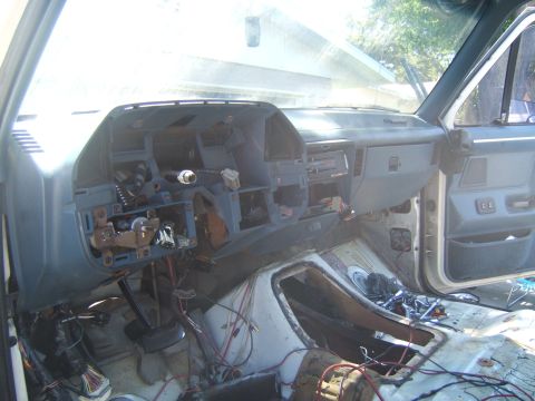 1988 Ford Bronco - Gutted interior of an older truck mid-restoration, viewed from the passenger side, with the gray dashboard partially disassembled, the stee…