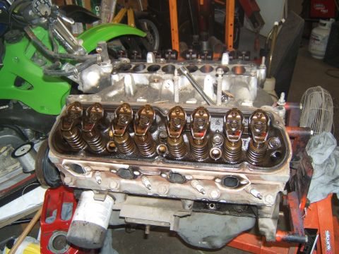 1988 Ford Bronco - V8 engine block with valve train components exposed, on an engine stand in a garage.