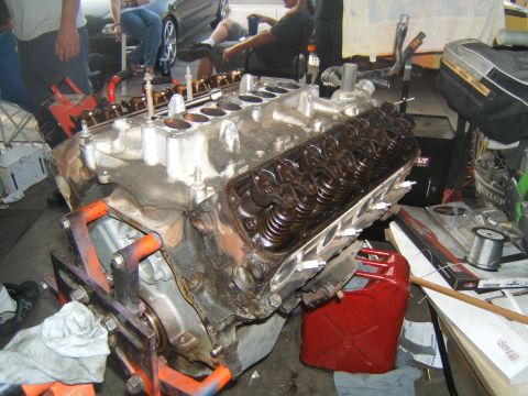 1988 Ford Bronco - A V8 engine block is shown on a stand, with a red gas can and various tools in the background.