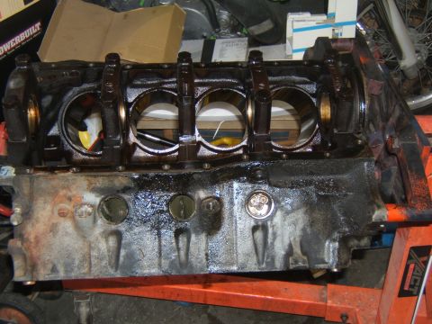 1988 Ford Bronco - Engine block on an orange stand, showing crankshaft bearings and cylinder bores.