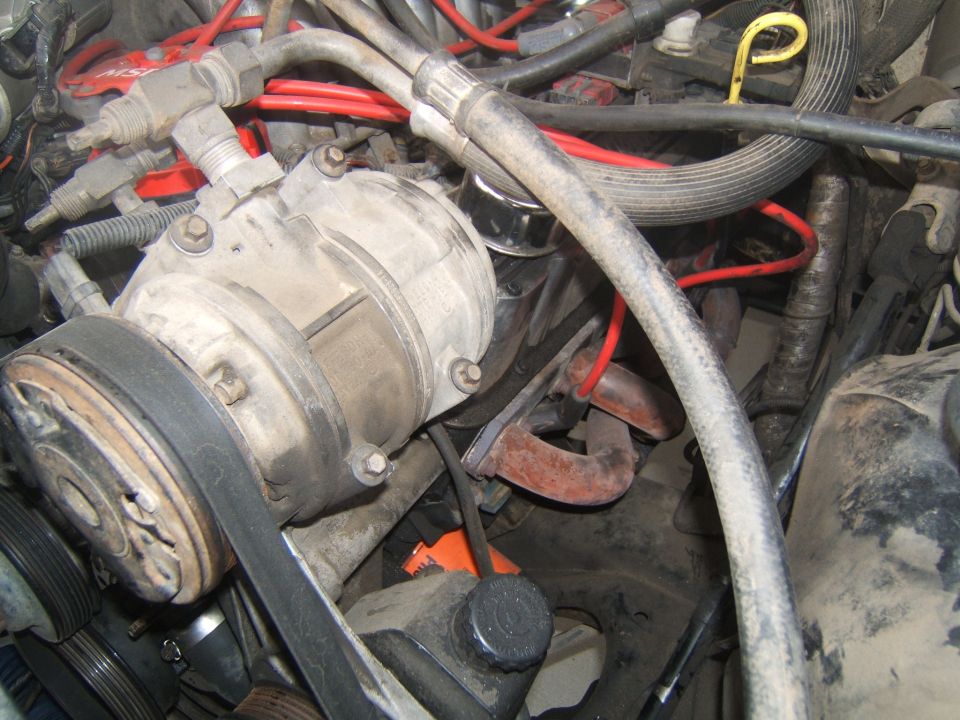 Engine compartment with air conditioning compressor, hoses, and spark plug wires