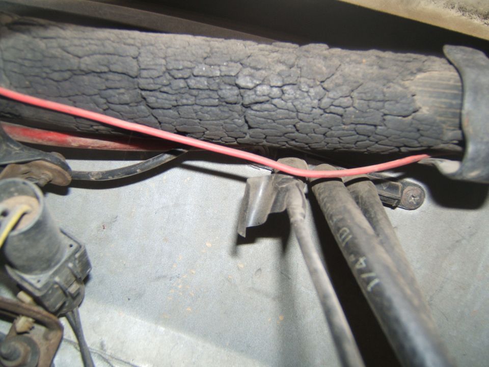Close-up of cracked insulation on a large hose, with red wire and other hoses visible