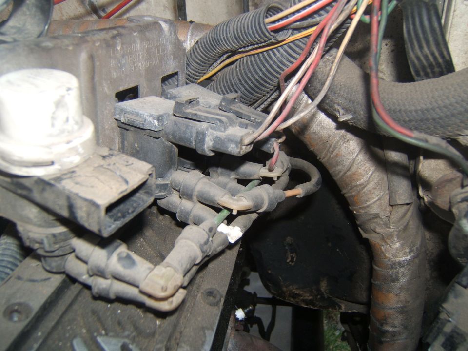 Close-up of engine wiring harness and spark plug wires, some text visible on a metal bracket