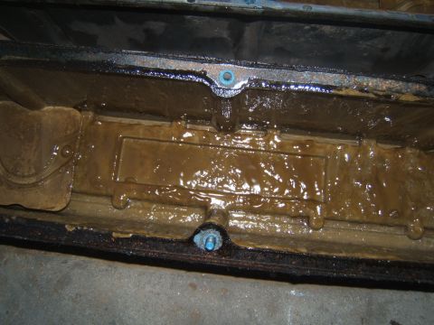 1988 Ford Bronco - Close-up of a heavily soiled engine oil pan, indicating potential maintenance issues.