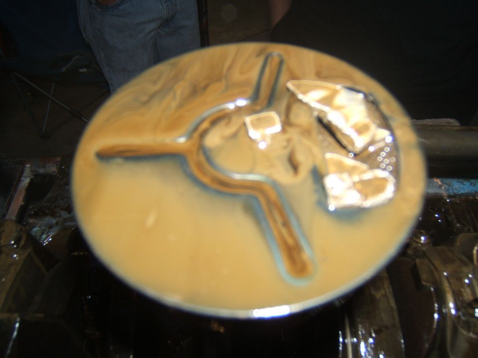 Circular engine part submerged in tan fluid with metallic debris