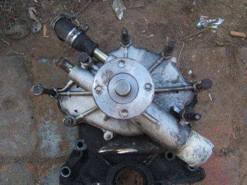 1988 Ford Bronco - A used engine water pump is shown, detached from a vehicle, with a hose connected.