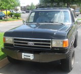 1990 Ford Bronco - A black 1990 Ford Bronco is parked outside, a custom brushguard and winch on the front bumper.