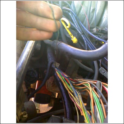 1989 Ford F-150 - Close-up of a vehicle's engine bay, showing a bundle of multicolored wires and a yellow dipstick.