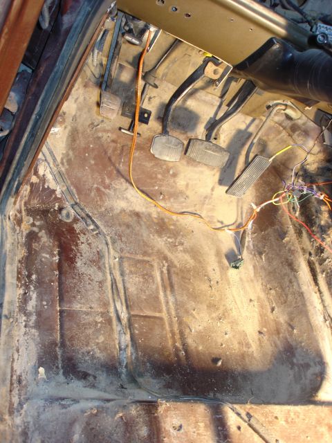 1979 Ford F-250 - The interior floor pan of a 1979 Ford F-250 shows pedals and exposed wiring.