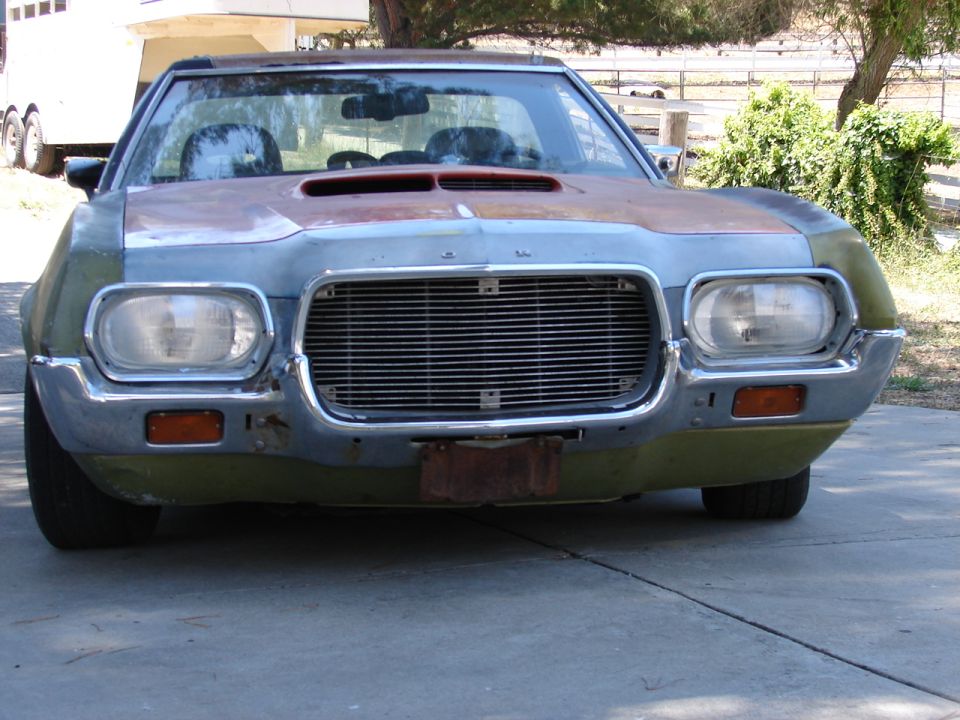 Front view of a faded green primered early-1970s Ford Ranchero project car in a driveway