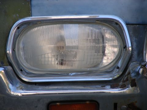 1973 Ford Ranchero - Close-up of the headlight and chrome trim on a 1973 Ford Ranchero, with visible rust on the bumper.