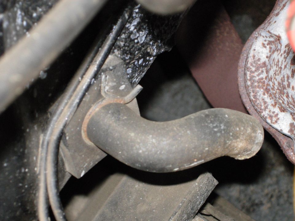 Close-up of hoses and exhaust manifold in an engine bay. Watermark says SUPERMOTORS.NET