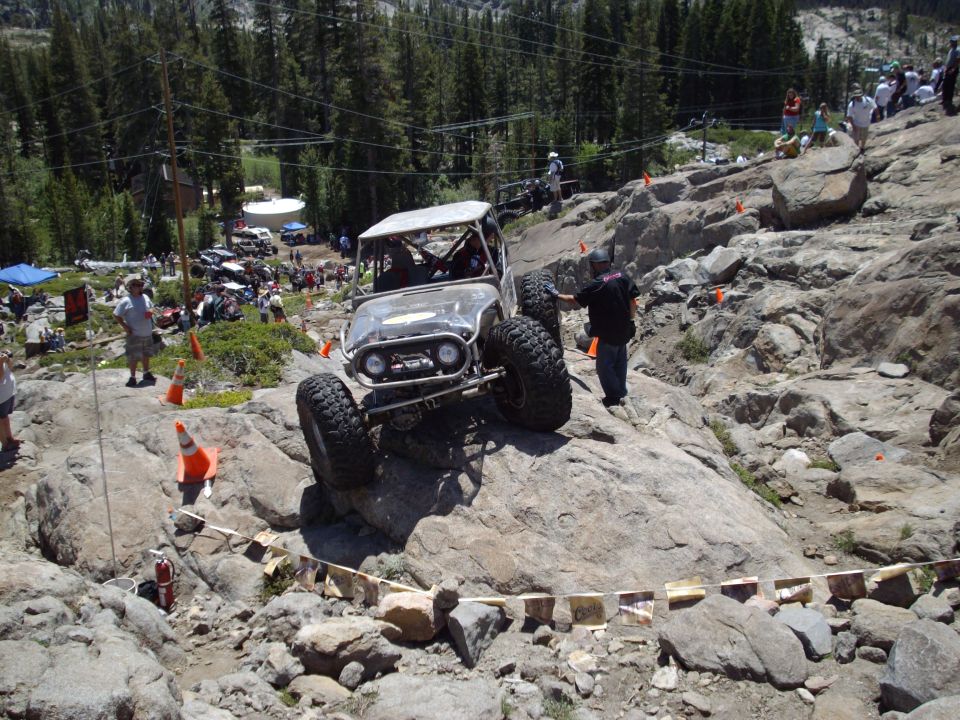 Off-road vehicle climbing rocky terrain with spectators