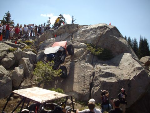 1982 Toyota Pickup/SR5 - An off-road vehicle navigates a steep, rocky terrain as a crowd observes the challenging climb.