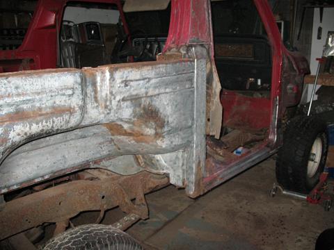 1978 Ford Bronco - This red truck body shows significant rust and damage, with parts of the interior visible.