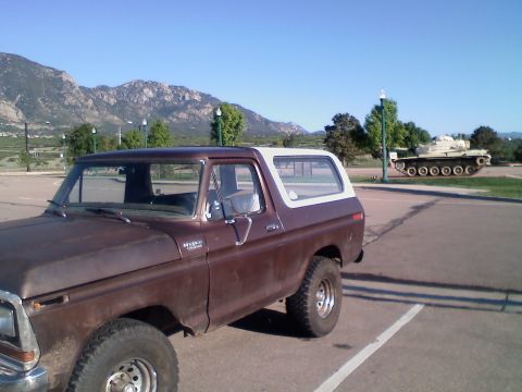 1979 Ford Bronco - A classic Ford Bronco sits in a parking lot, with a military tank on display in the distance.