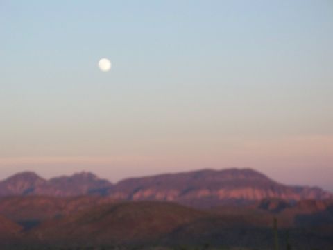 1996 Ford Bronco - The moon hangs in the sky above desert mountains as the sun sets.