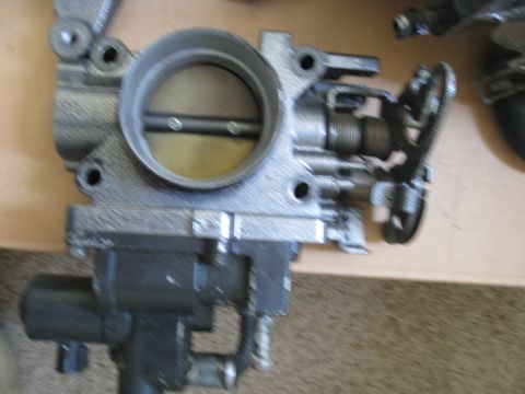 1994 Ford Probe - Close-up of a vehicle throttle body assembly, showing internal components and external mounting points.